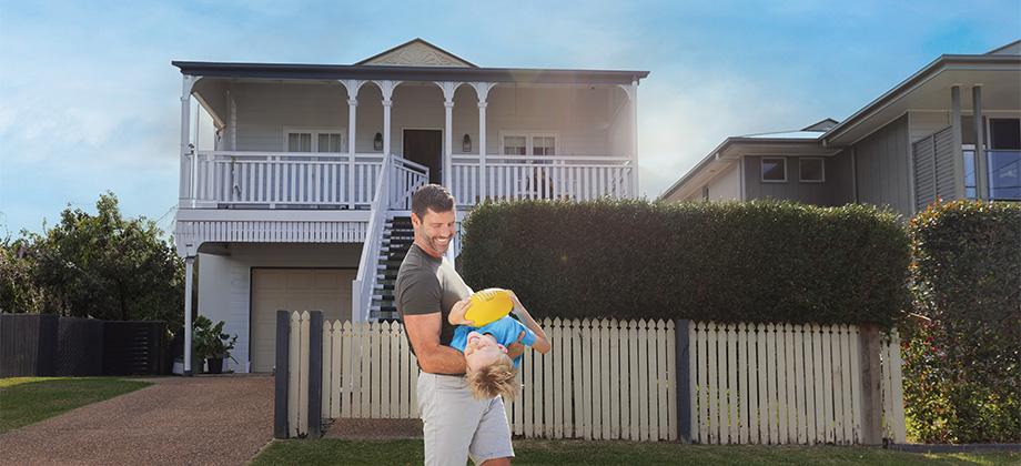 Dad playing with child in front of house