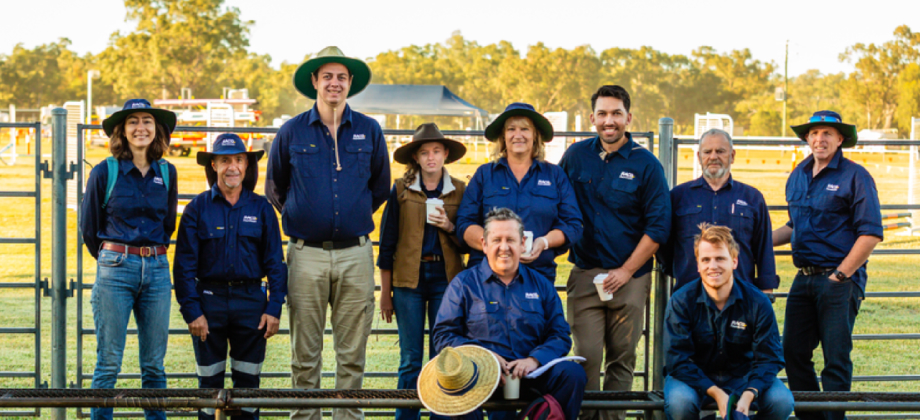 Group of RACQ community volunteers standing and sitting together in a rural outdoor setting