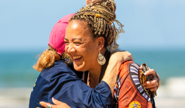 Two people hugging outdoors near the ocean
