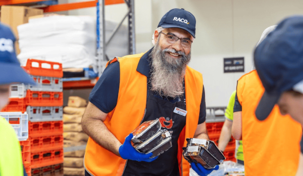 Volunteer holding packaged meals in a warehouse