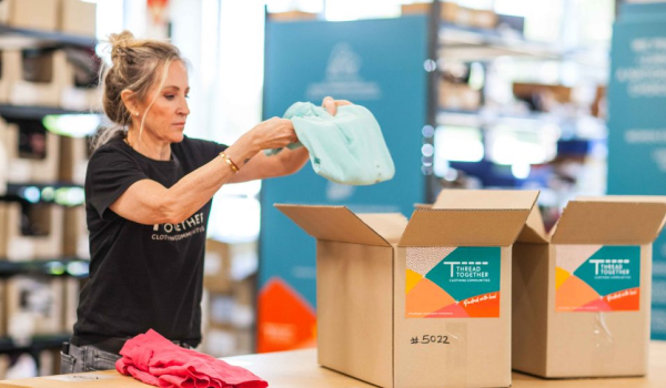 Thread volunteer packing clothes into boxes for donations
