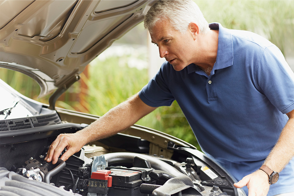Man checks under the bonnet of a car.