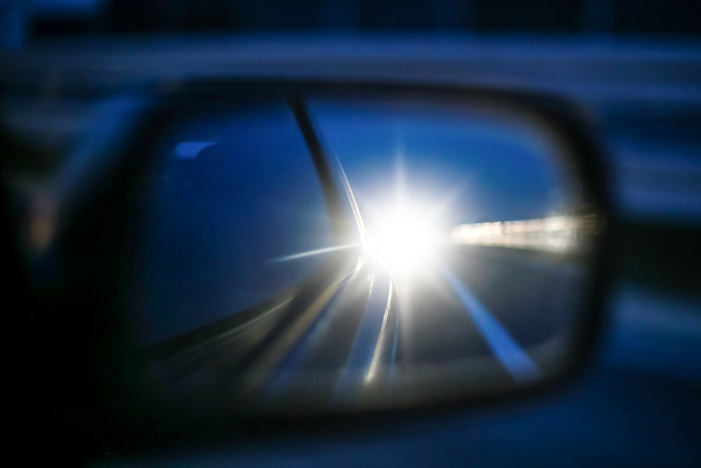 Bright headlights refelected in side mirror.