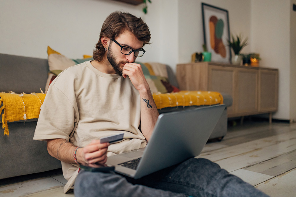 Man looking at laptop while holding a credit card.