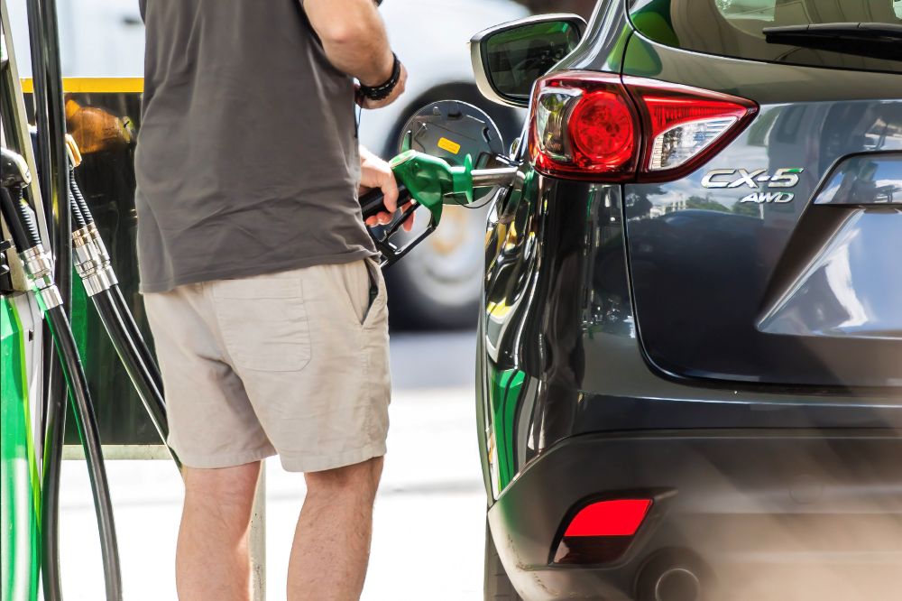Man holds petrol pump beside car