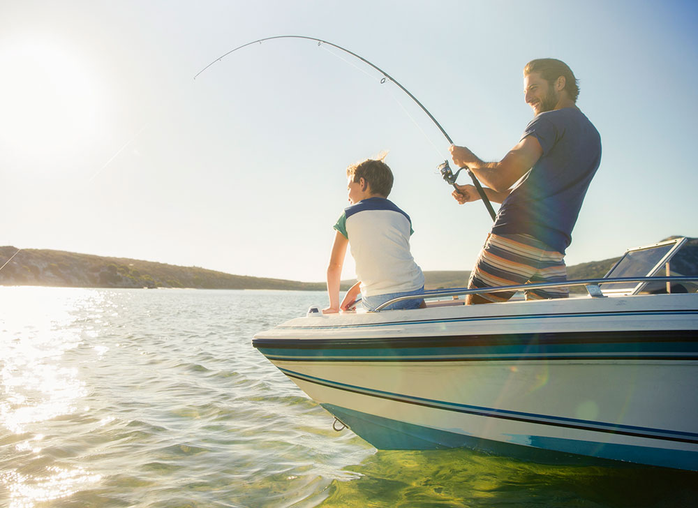 Man fishing from boat with boy.