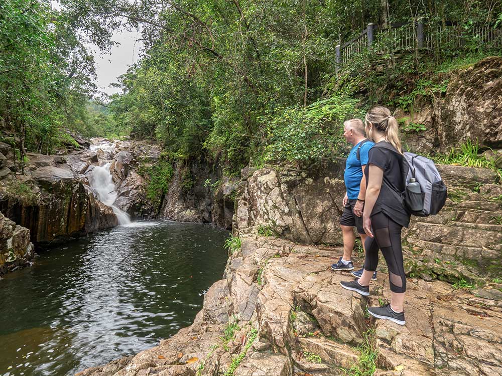Hikers looking at a small watefall and pool in Finch Hatton Gorge