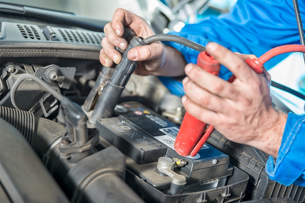 mechanic attaching jumper cables to car battery