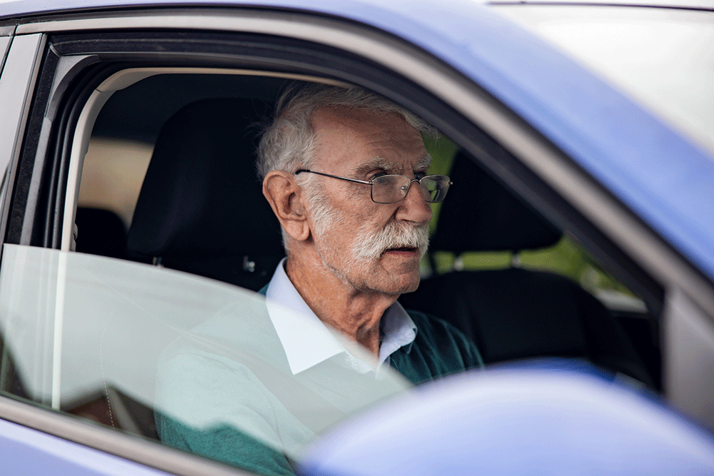 Elderly male driver behind the wheel of his car.