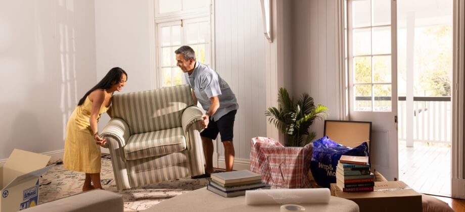 Man and woman moving furniture into house